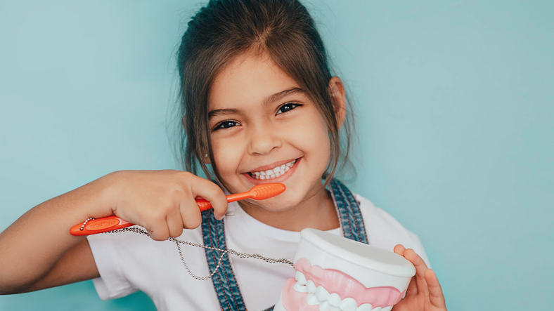 smiling girl brushing teeth against blue background